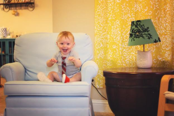 Baby sitting in a glider rocker in the living room